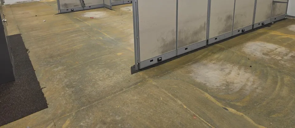 Before: carpet glue and seam marks on a warehouse office slab